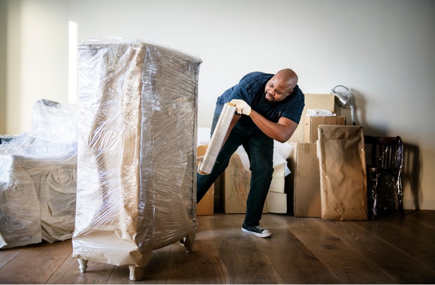 a mover wrapping a piece of furniture in plastic wrap