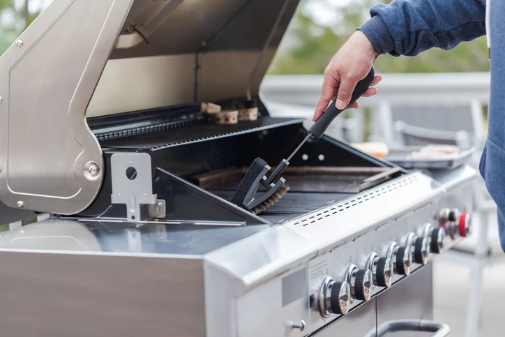 man scrubbing down grill grates with a brush