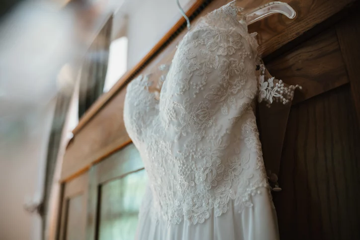 a white wedding dress hanging on the door of a closet