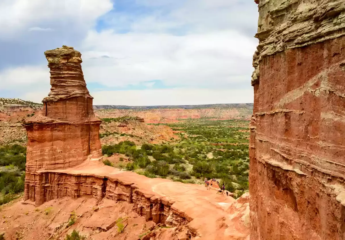 A beautiful view of Palo Duro Canyon State Park in Amarillo, Texas, with red rock formations in front of greenery