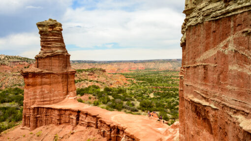 A beautiful view of Palo Duro Canyon State Park in Amarillo, Texas, with red rock formations in front of greenery