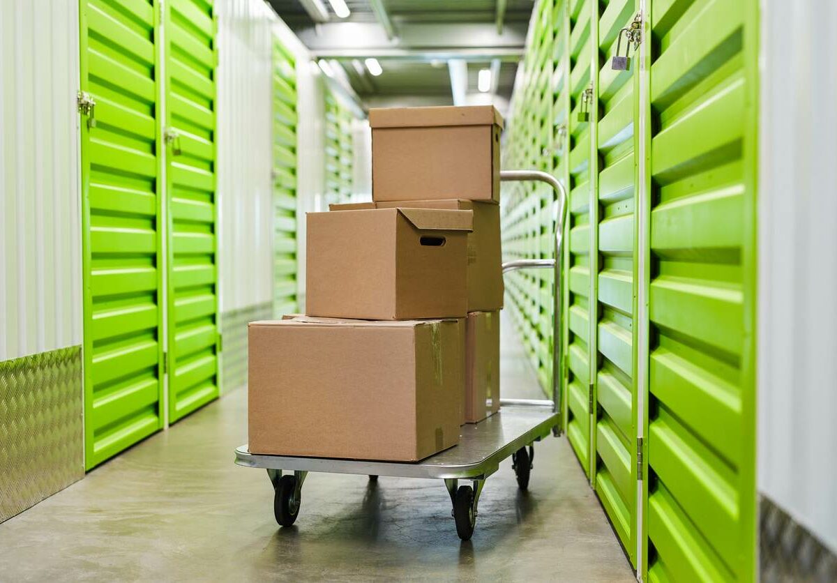 A moving cart with boxes stacked on top, inside a self storage facility.