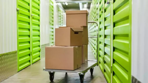 A moving cart with boxes stacked on top, inside a self storage facility.