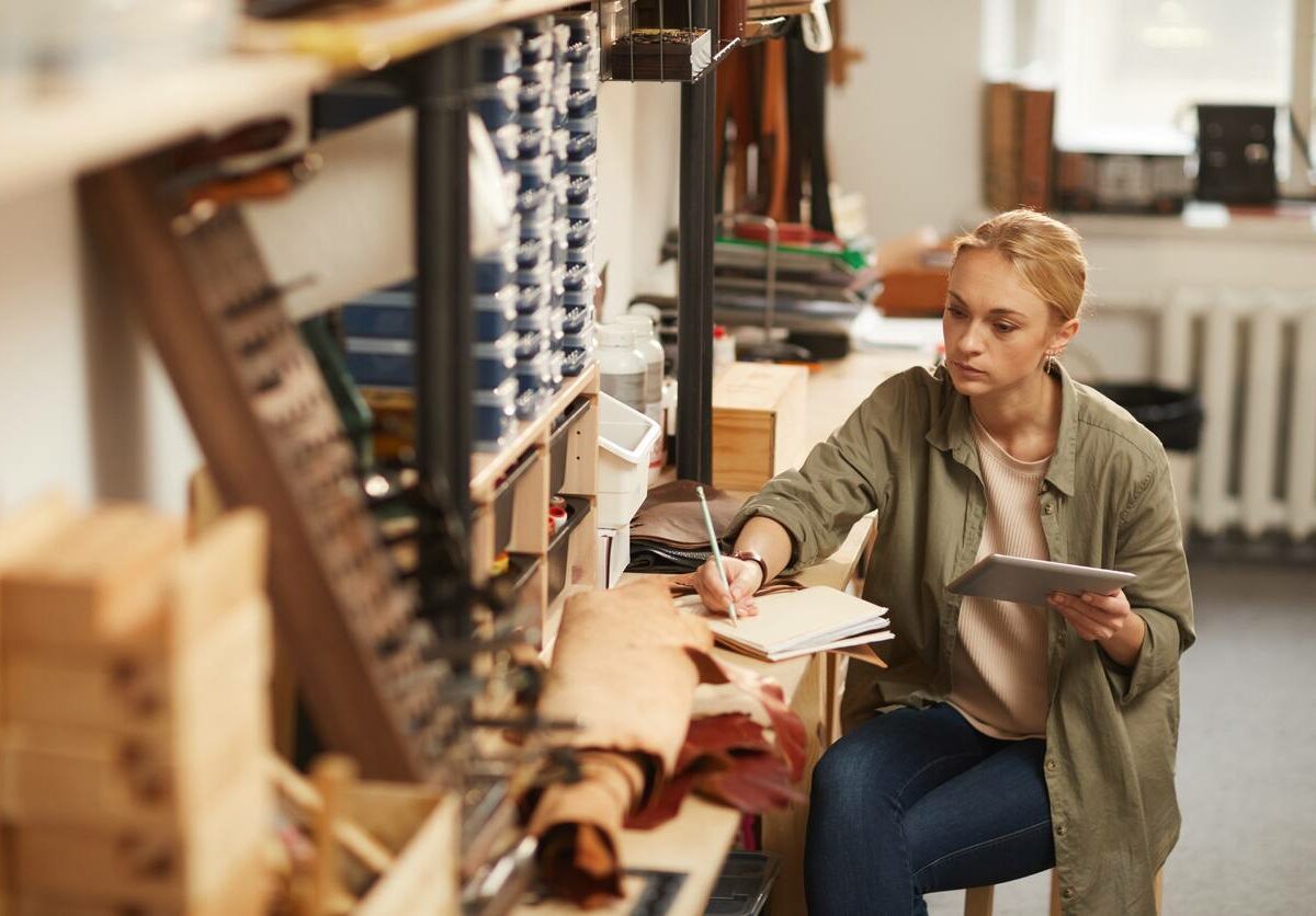 A woman sits and works at a desk in a woodworking office space.