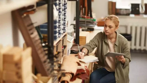 A woman sits and works at a desk in a woodworking office space.