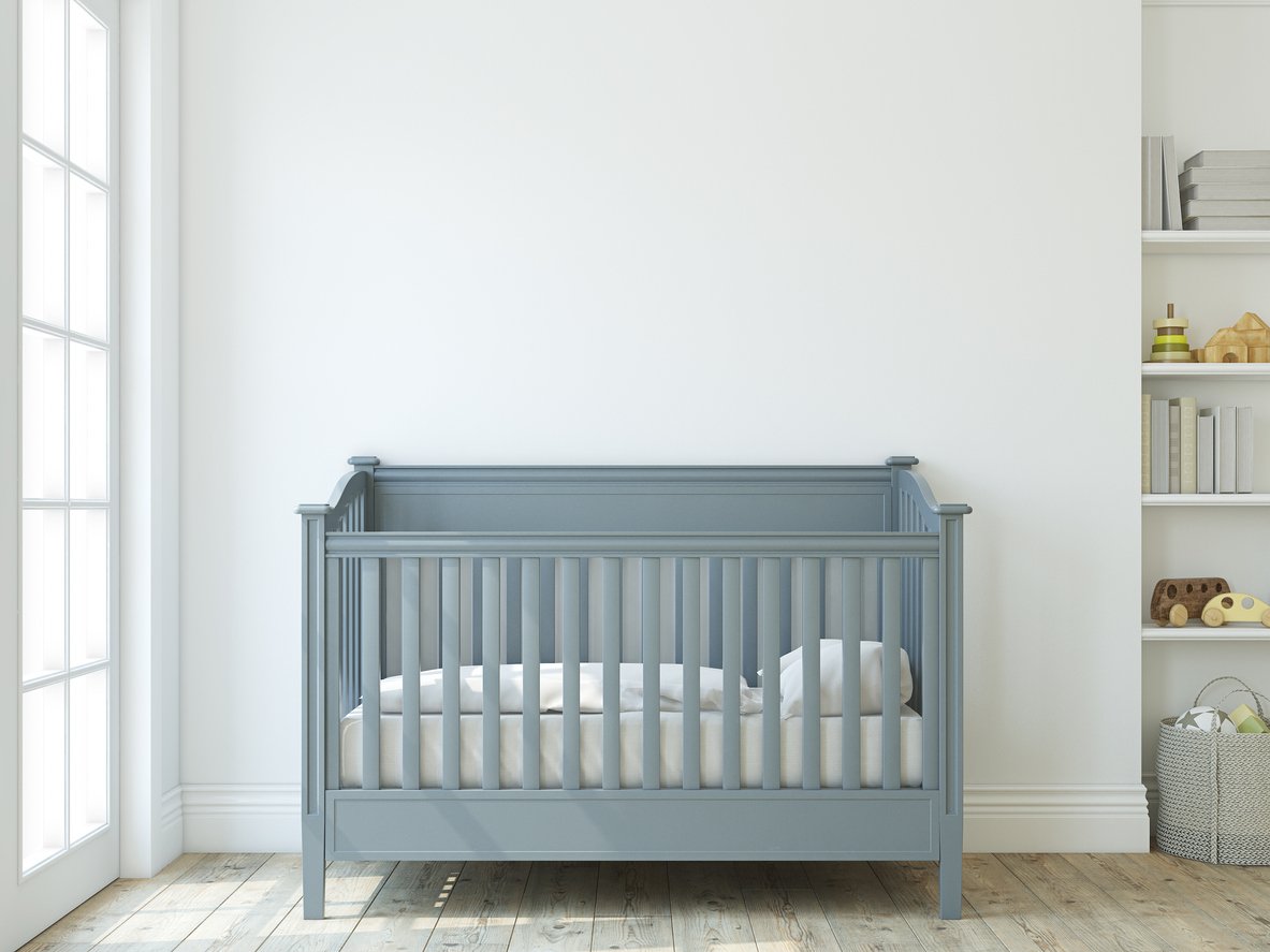 A blue baby crib sits against a white wall in a residential space.