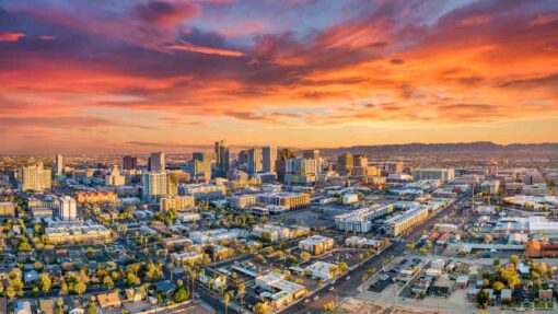 A photo of the Phoenix skyline with a blue, purple, orange, and yellow sunset in the background.