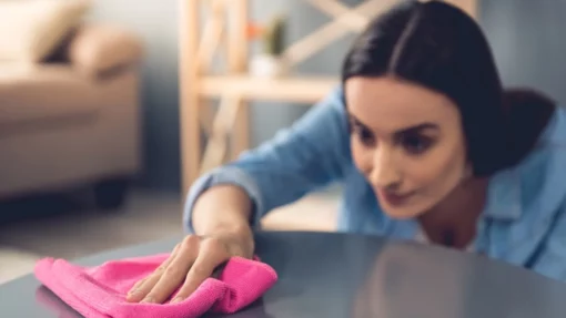 Shot of a woman cleaning her table with a cloth.