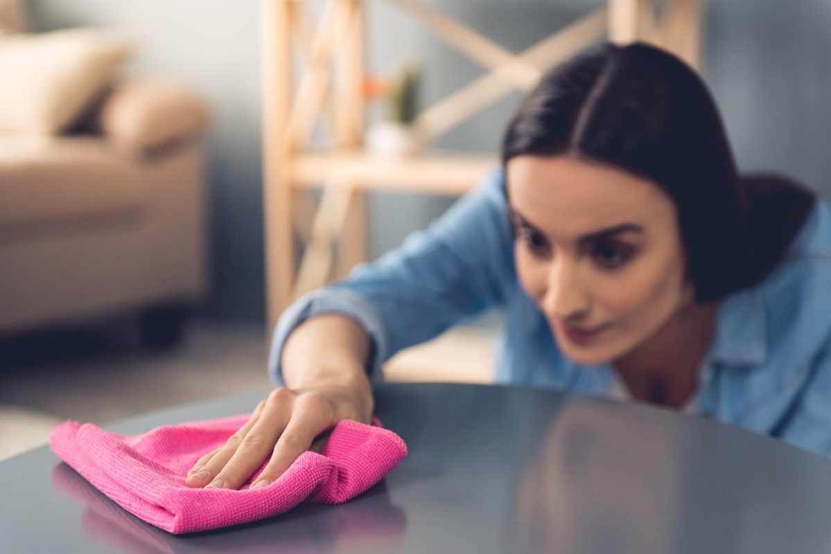 Shot of a woman cleaning her table with a cloth.
