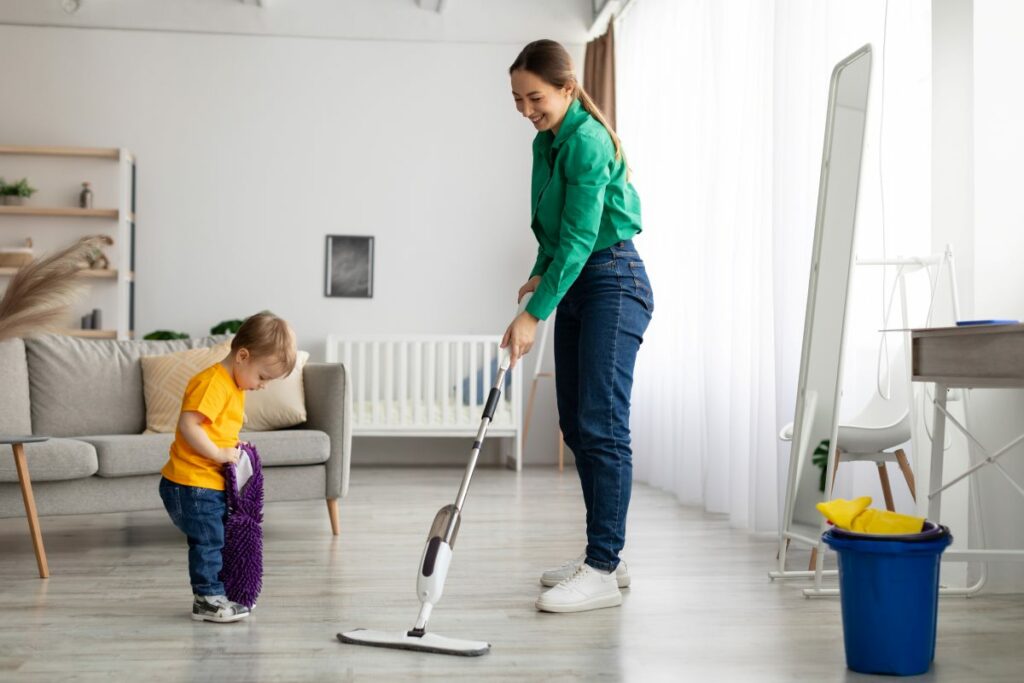 A mother and son sweep the floors together during spring cleaning.