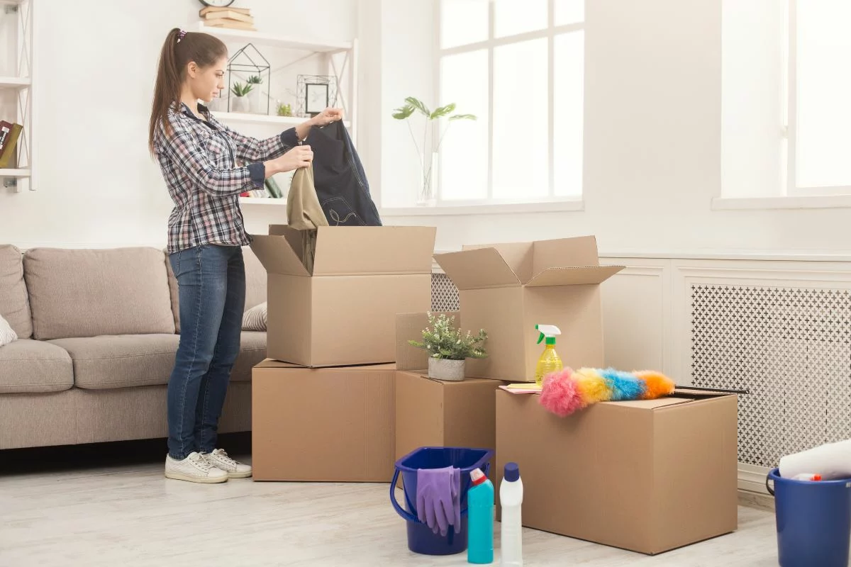 A woman organizes her things into boxes while spring cleaning her home.