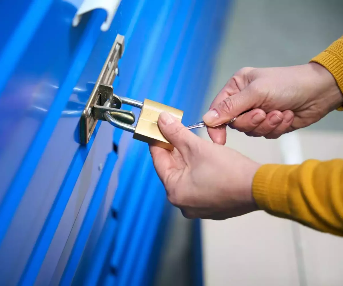 A person uses a key to secure the lock on their self storage unit.