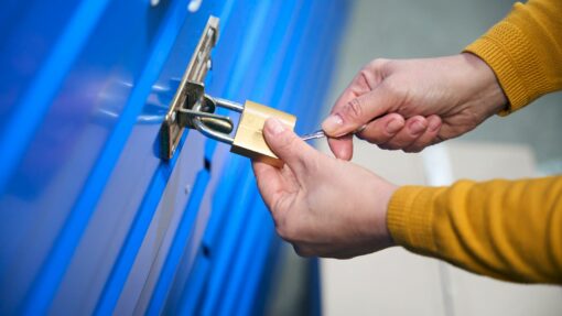 A person uses a key to secure the lock on their self storage unit.