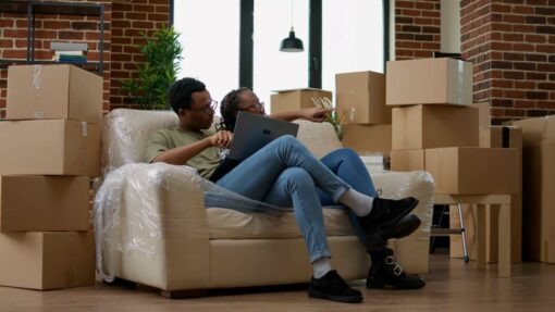 A couple takes a break on the couch while moving.