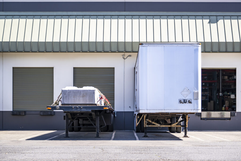 A semi-truck unloading inventory into a drive-up storage unit.