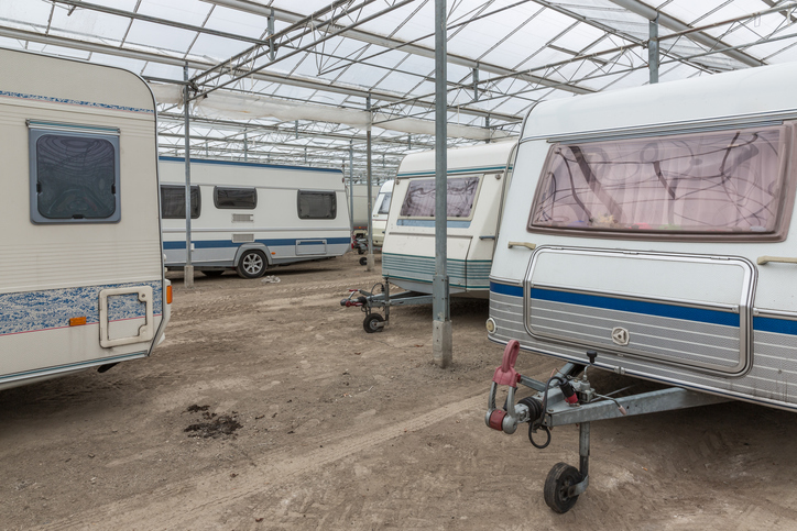 RVs parked in a storage facility under a glass roof.