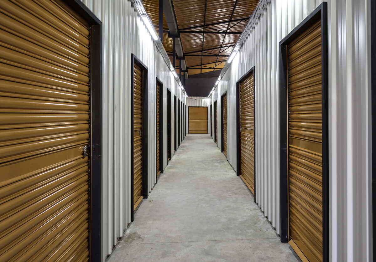 A hallway of indoor storage units with orange doors.