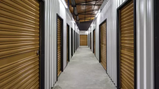 A hallway of indoor storage units with orange doors.