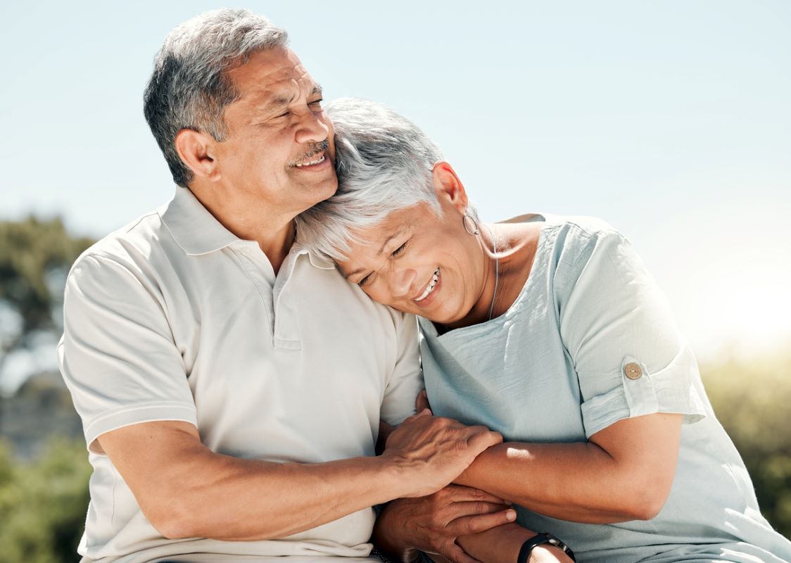 A senior couple holding hands, smiling, and enjoying nature.