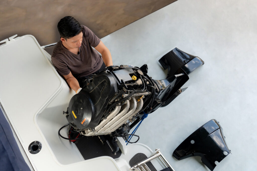 A man repairing the engine of a motorboat.