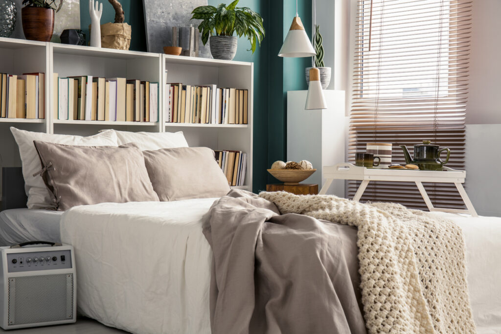 A small, bright bedroom with bookshelves, a bed, and decorations.