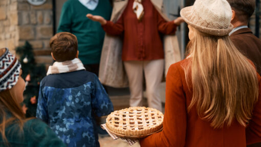 Grandparents greet their family as they arrive for Thanksgiving, holding a pie.