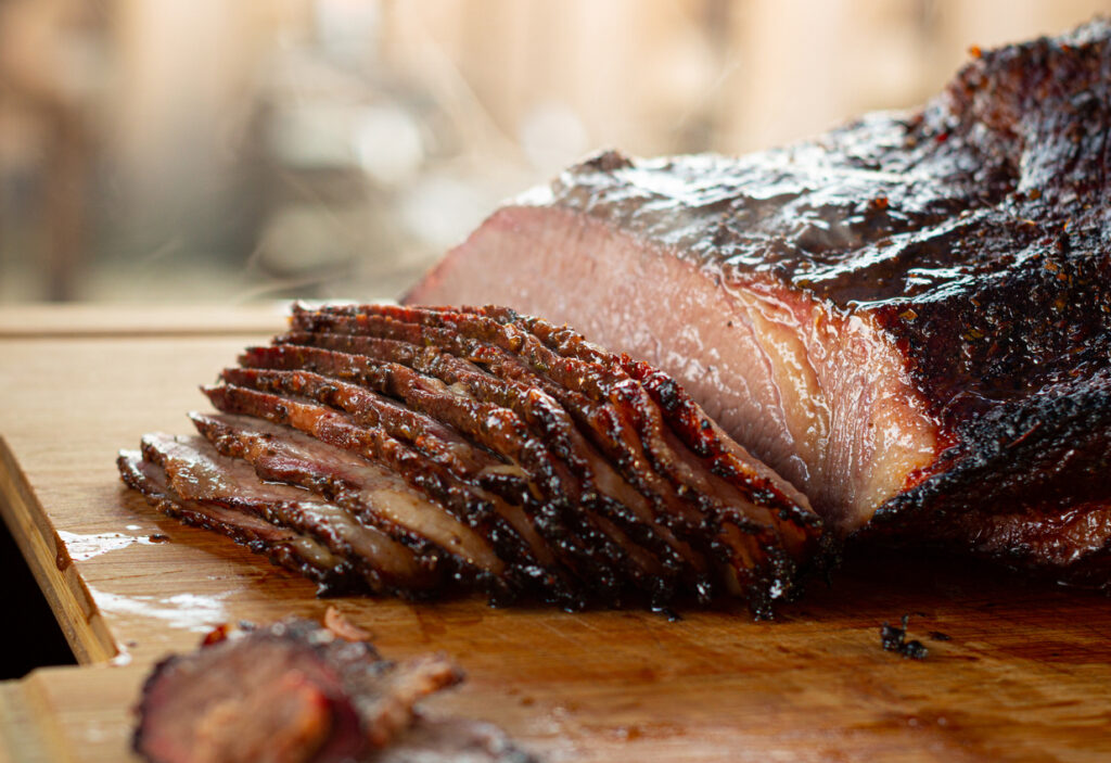 A barbecue brisket sliced on a wooden cutting board.