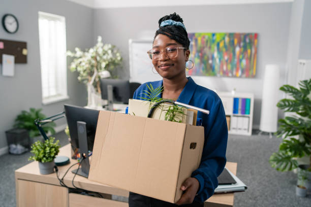 A woman holding a box after packing up part of her office.