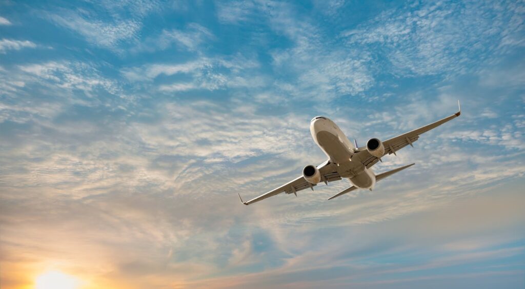 Commercial plane flying at sunset.