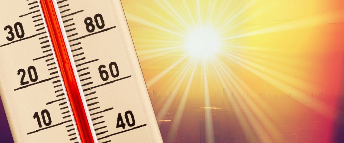 A thermometer measuring the temperature with the blazing sun shining behind.