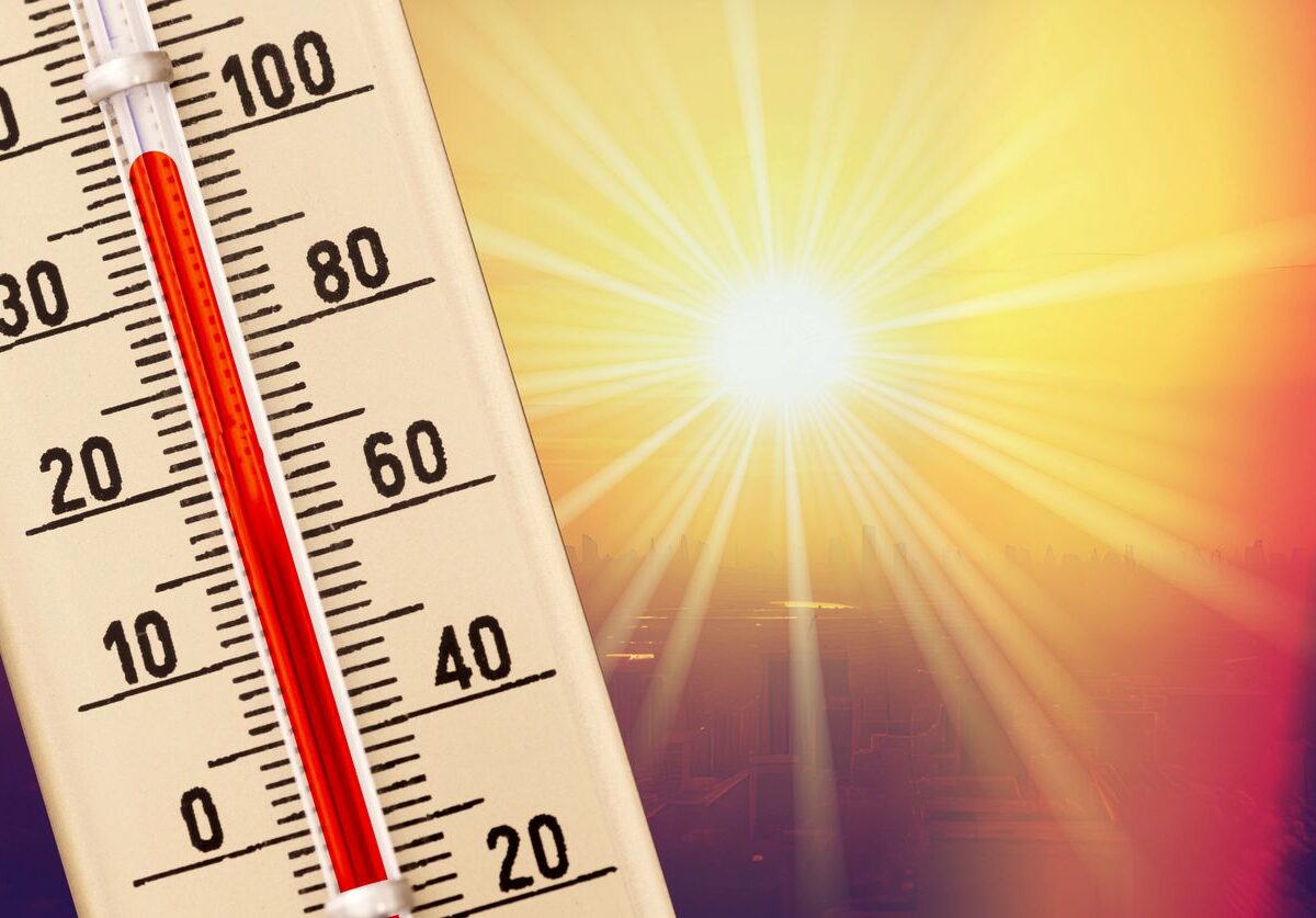 A thermometer measuring the temperature with the blazing sun shining behind.