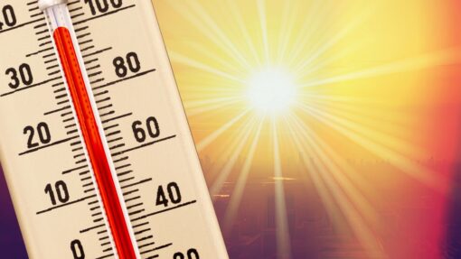 A thermometer measuring the temperature with the blazing sun shining behind.