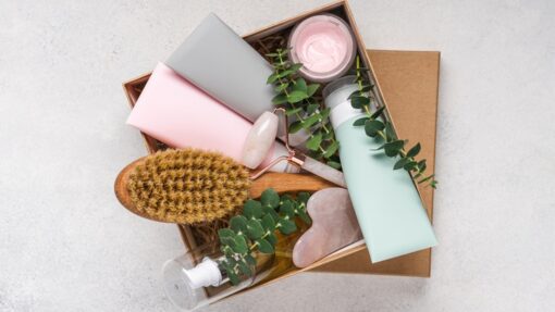 A box of personal care belongings, including a hairbrush, skin care products, and a rose quartz face roller.