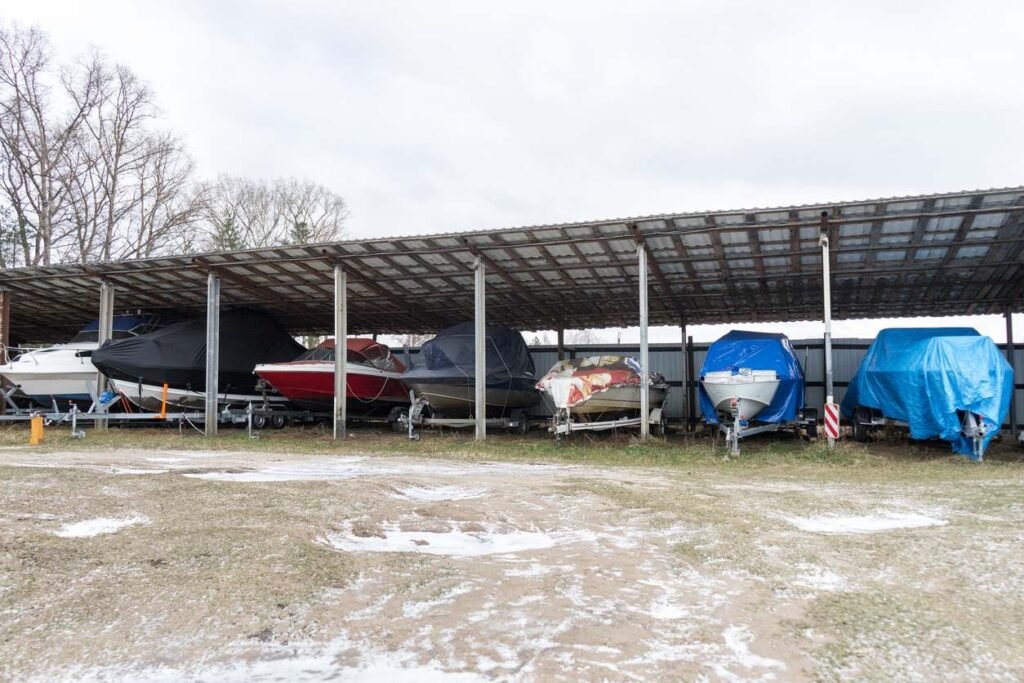 A covered boat storage area with multiple boats under a metal canopy.